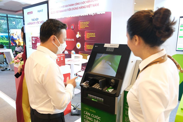 Cán bộ Vietcombank tư vấn khách hàng sử dụng dịch vụ ngân hàng số (ảnh trên) và dịch vụ ATM tại gian hàng trưng bày